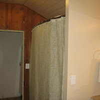 The new shower along with a new wall to divide the shower and vanity. Before the remodel the sink was against the tongue and groove paneling (by the door).